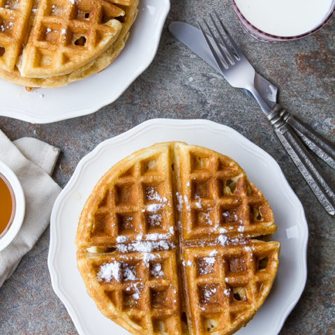 waffles sitting on white plates with a knife and fork