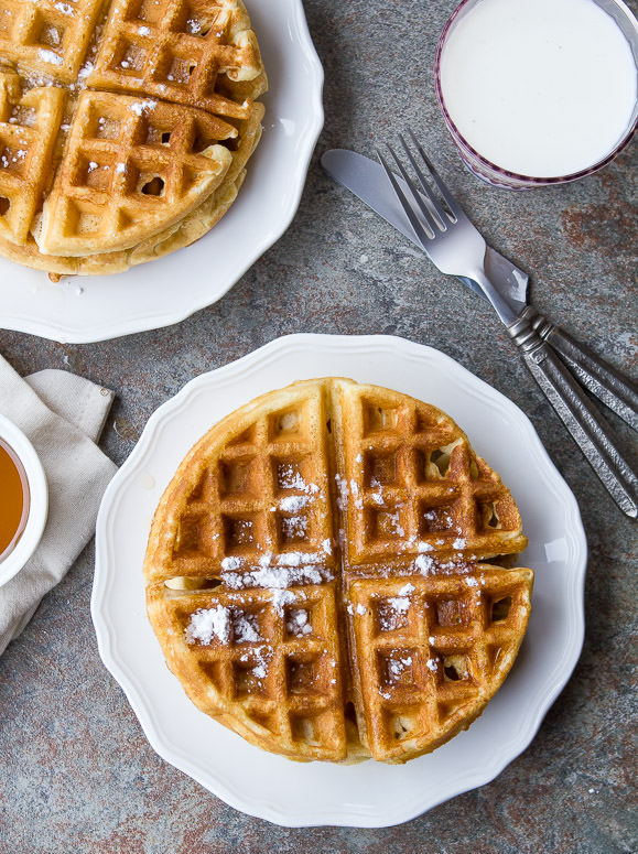 waffles sitting on white plates with a knife and fork