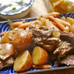 Cooked short ribs, carrots, and potatoes on a blue serving dish