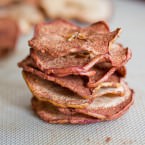 Dried apple chips on top of each other on a baking mat
