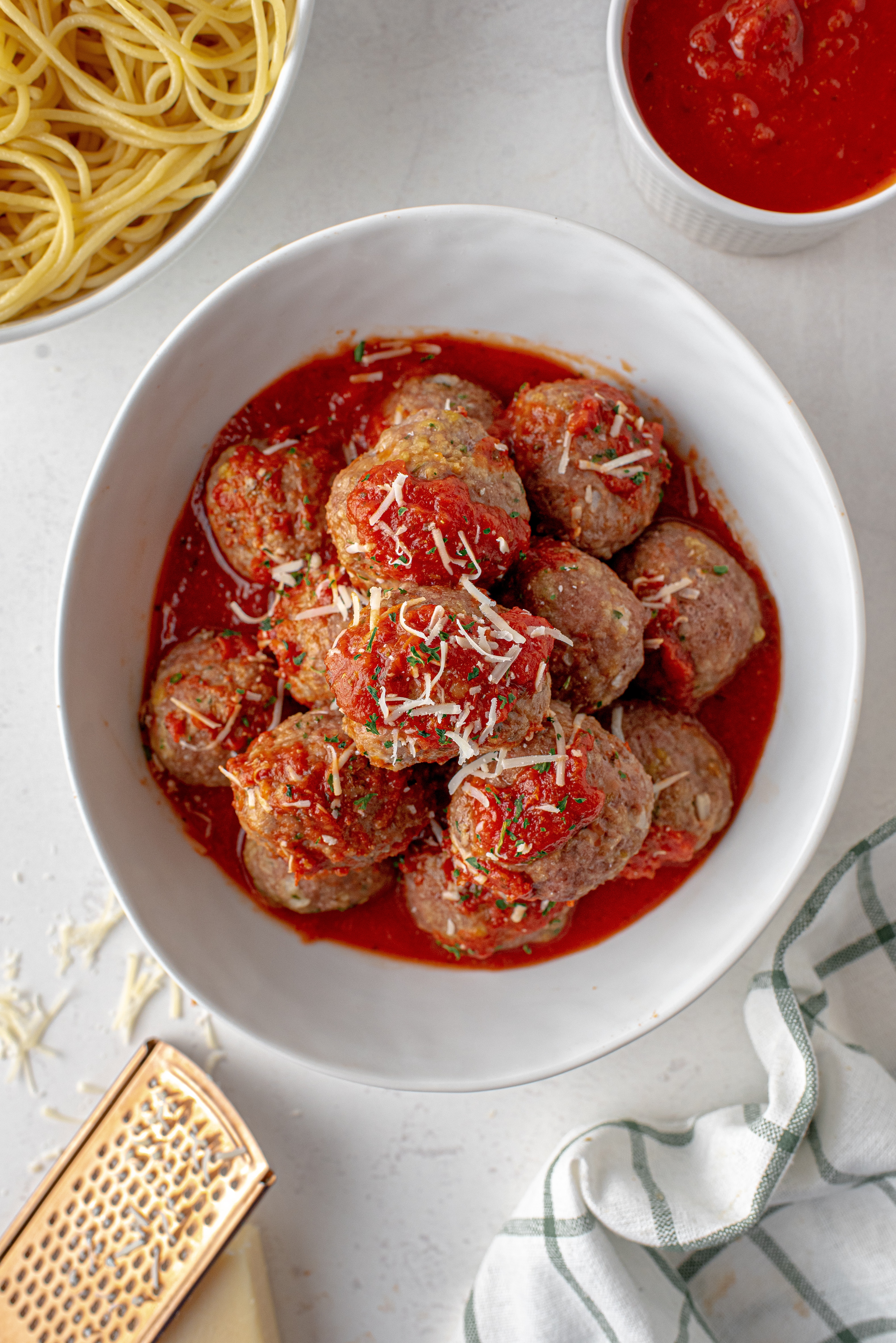 meatballs on top of each other in a white bowl with marinara