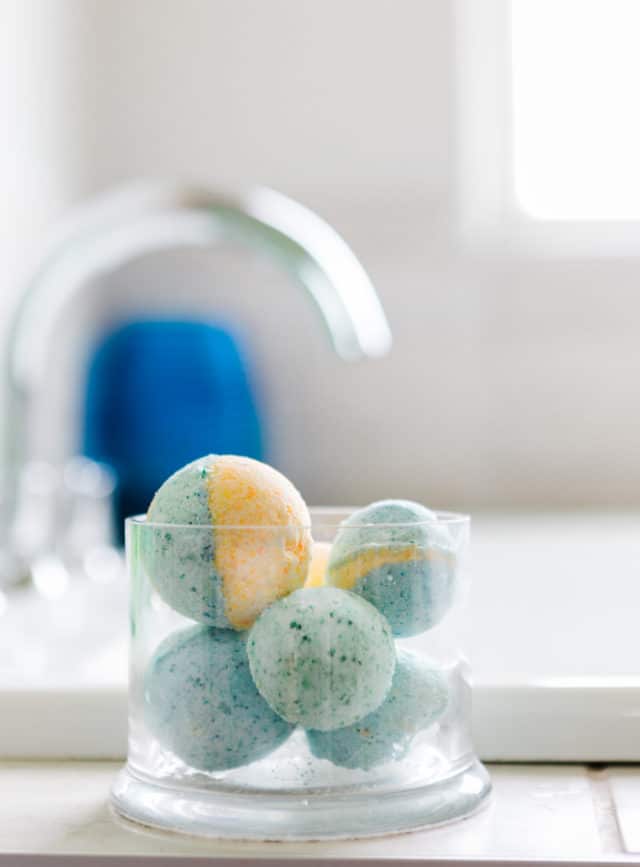 bath bombs in a clear glass container by the bath tub