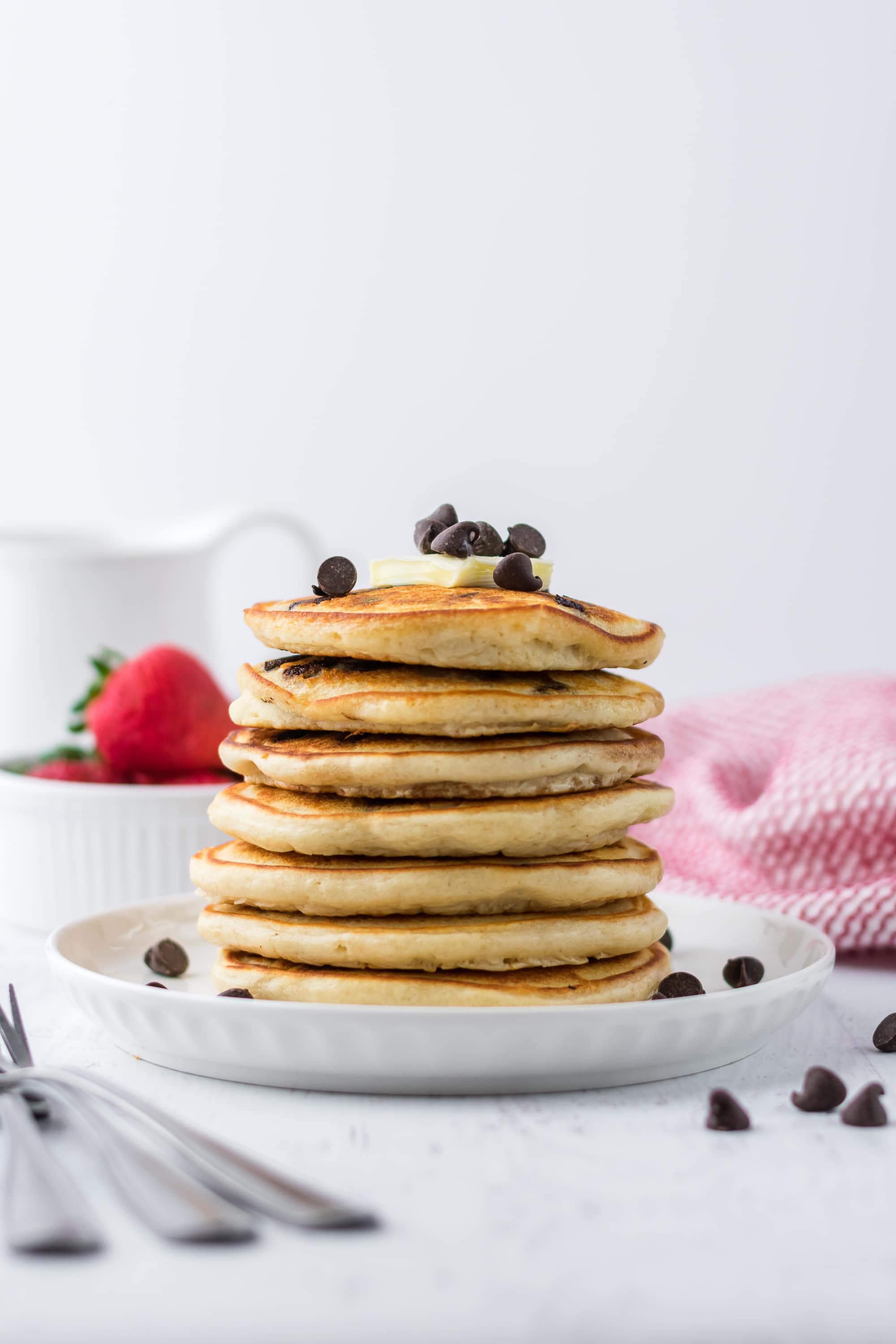 stacked chocolate chip pancakes on a plate with silverware